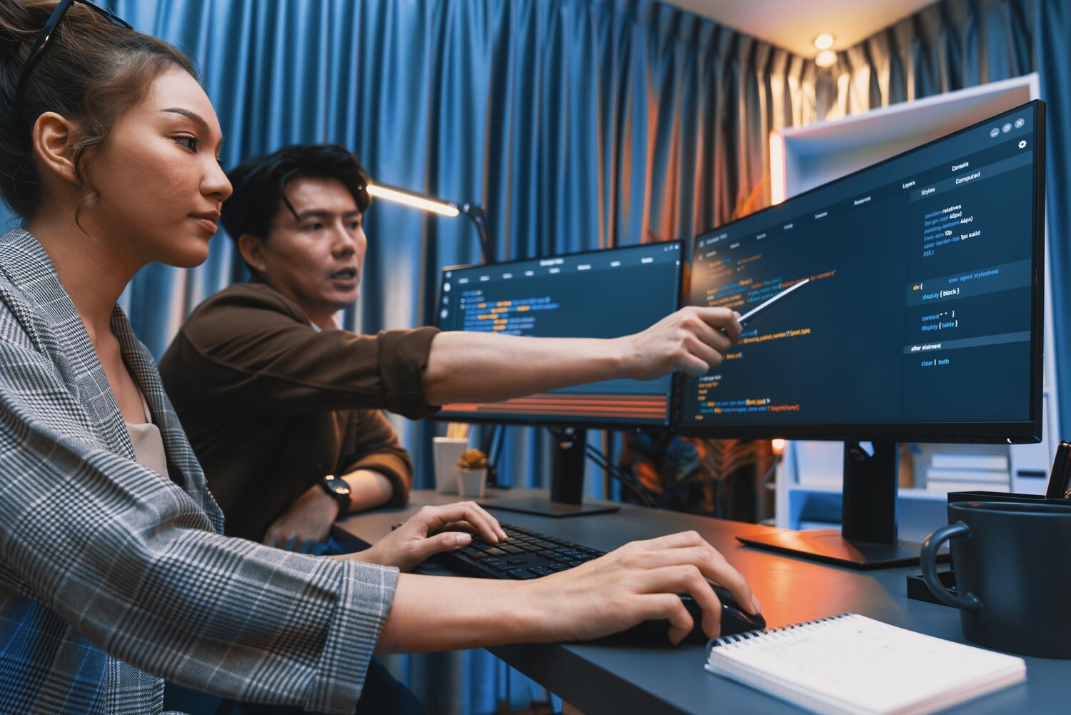 Engineering duo collaborating on code review and deployment strategy with CI/CD metrics visible for a major delivery milestone