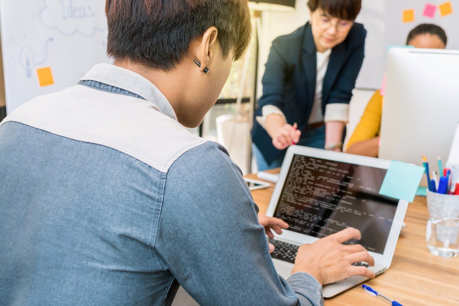 Engineers collaborating on API and queue-based integration design at a whiteboard and laptops in a modern tech workspace